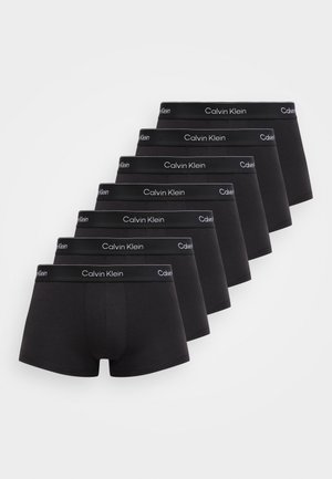 Septiņi melnu Calvin Klein bokseru pāri ar zīmola jostasvietām izvietoti diagonāli uz balta fona.