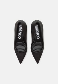 Zapatos de tacón negro con punta afilada, acabado mate liso, plantillas acolchadas y marca "BIANCO" en las plantillas.