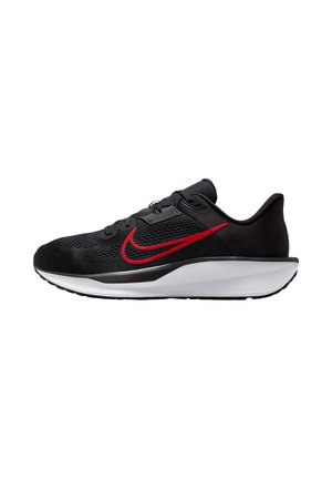 Zapatilla deportiva negra con parte superior de malla transpirable, un prominente logo rojo de Nike y una mediasuela blanca. Presenta detalles texturizados y un sistema de cordones.