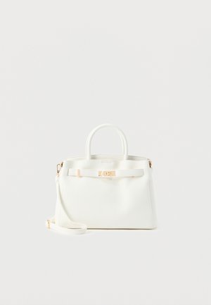 Valge tekstuuriga käekott pealsete käepidemete, kuldse tooni kinnitusklapi ja eemaldatava õlarihmaga, ühtlasel heledal taustal.