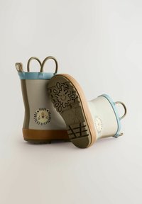 Bottes de pluie en caoutchouc beige avec des accents bleus, ornées d'un motif de lion sur le côté et d'une semelle brune texturée avec un détail ludique.