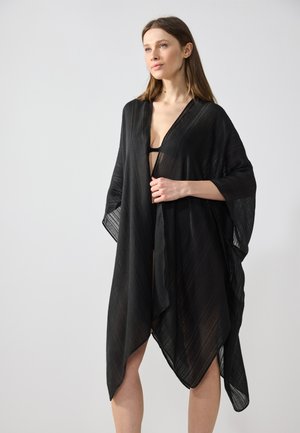 Kimono noir ouvert en tissu léger et texturé. Présente un décolleté en V et des manches fluides, créant une silhouette décontractée.