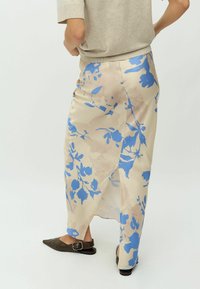 Beige en blauwe bloemen midi rok met een zijsplit, gemaakt van lichtgewicht stof. Gecombineerd met donkerbruine puntige ballerina's.