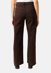 Bruna leopardmönstrade vida byxor med hög midja, med en slät textur och två bakfickor. Svarta accenter vid midjan.