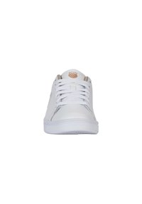 Baskets blanches en cuir avec une surface lisse, semelle plate blanche et bout arrondi. Comprend des lacets neutres et un petit logo sur la languette.