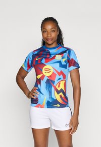 Kolorowa koszulka piłkarska z krótkim rękawem, z abstrakcyjnymi wzorami w kolorze niebieskim, czerwonym i żółtym, z okrągłym dekoltem i logo drużyny. Noszona z białymi szortami.