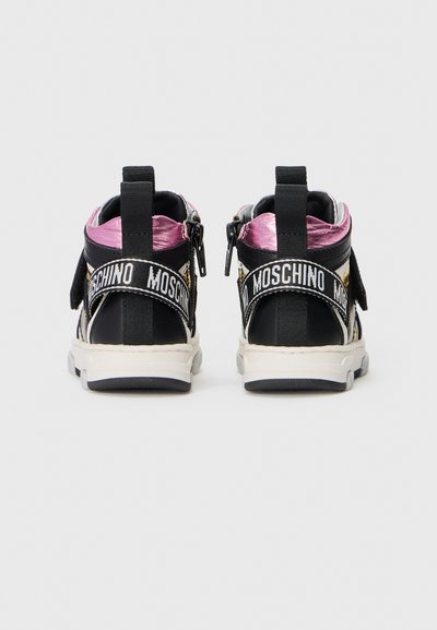 Baskets montantes noires avec des accents roses brillants, présentant une fermeture éclair, des sangles en tissu et une semelle texturée. Marque affichée de manière évidente.