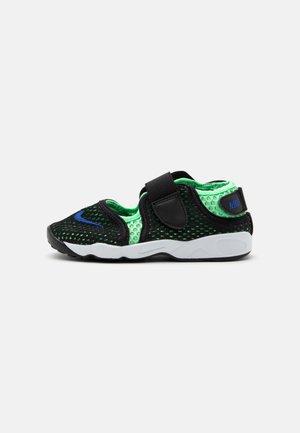 Sandalia Nike transpirable en negro y verde neón con tira de velcro y suela blanca, vista lateral sobre fondo liso.