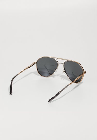 Lunettes de soleil avec verres gris, monture en métal et accréditations dorées. Dotées d'un double pont et de branches noires au fini lisse.