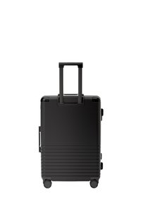 Zwarte koffer met een gegroefd ontwerp, telescopische handgreep en vier wielen voor mobiliteit. Voorzien van duurzaam materiaal en minimalistische accenten.