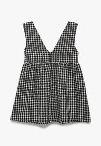 Schwarz-weißer karierten Kleid mit V-Ausschnitt, ärmellosem Design, tailliertem Oberteil und ausgestelltem Rock. Hergestellt aus strukturiertem Stoff mit einem Muster.