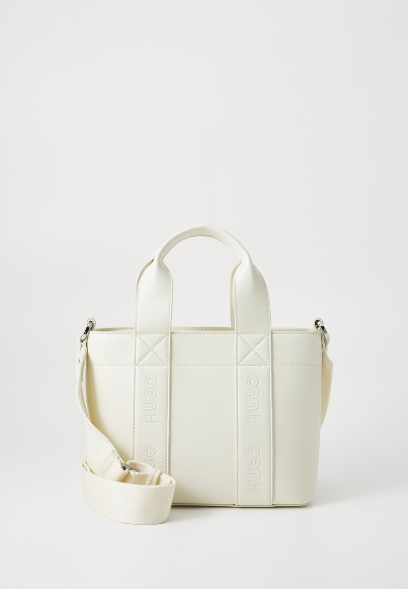 Sac à main structuré blanc avec deux poignées courtes et une sangle épaule amovible. Présente un logo en relief sur le devant et une texture lisse.