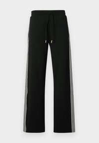 Schwarze Jogginghosen mit weitem Bein, elastischem Bund und Kordelzug. Mit kontrastierenden gestreiften Seitenpaneelen und goldfarbenen Beschlägen.