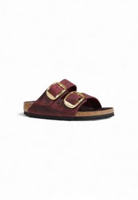 Bordeaux leren sandalen met twee verstelbare gouden gespen, kurken voetbed en een zwarte rubberen zool, met een open teen ontwerp.