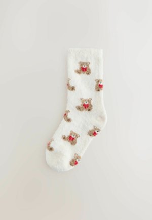 Uldne hvide strømper med et gentaget bjørnemønster i lys brun med røde detaljer. Blød tekstur, ankellang design.