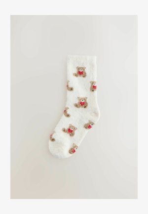 Kohmakad valged sokid, millel on helepruunide karude korduv muster punaste aksentidega. Pehme tekstuur, pahkluuni ulatuv disain.