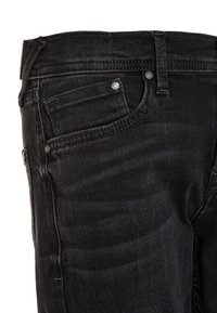 Czarne dżinsy o standardowym kroju pięciu kieszeni, z srebrnymi elementami oraz subtelnym przejaśnieniem na fakturze materiału.