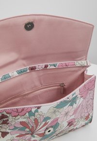 Floral-patterned handbag with a metallic snap closure. Features a pink interior lining and a zippered pocket for storage.