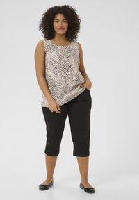 Ærmeløs leopardprint top i beige og sort, parret med sorte cropped bukser. Blødt stof med en afslappet pasform og sidelommer.