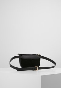 Musta nahkainen ja mokkanahkainen olkalaukku, jossa on litteä muotoilu, säädettävä olkahihna ja kullanväriset metalliosat. Sileä pinta ja minimalistinen tyyli.