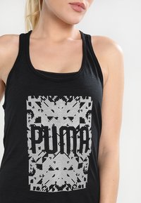 Black tank top with a wide neckline, featuring a prominent white graphic that spells "PUMA" in bold letters centered within a textured pattern.