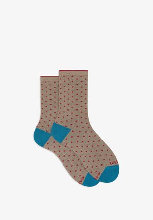 Beige Socken mit roten Punkten, dunkelblauen Fersen und Zehen, mit Strickstruktur und einem kontrastierenden roten Bündchen.