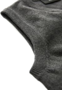 Pull gris en maille avec un col et un ourlet côtelés. Texture douce, vue en gros plan mettant en valeur le détail du tissu et les coutures.