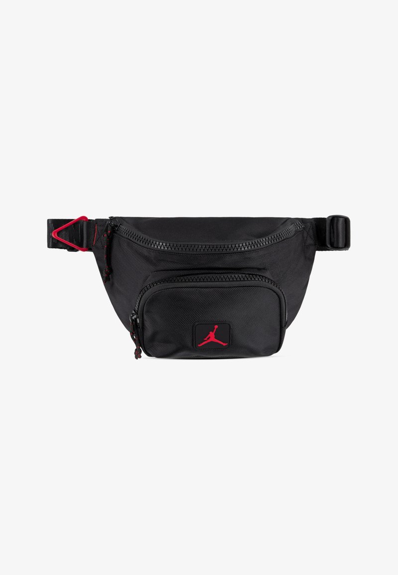 Black fabric fanny pack with a front zip pocket, red accents, and a Jordan logo patch. Features an adjustable strap and textured surface.