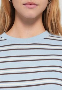 Ανοιχτό μπλε κοντομάνικο τοπ με οριζόντιες ρίγες σε καφέ, κρεμ και ανοιχτό μπλε. Μαλακό ύφασμα με κανονικό λαιμόκοψη τύπου crew.