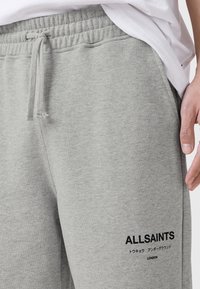 Γκρι φόρμα παντελόνι από μαλακό, υφασμάτινο ύφασμα με υφή. Διαθέτει ελαστική μέση με κορδόνι και τυπωμένο λογότυπο στο πλάι.