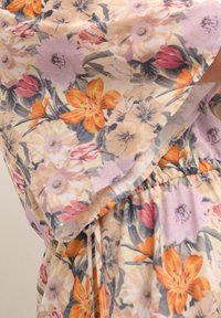Robe fleurie en tissu doux aux tons pastel avec des fleurs orange, rose et violettes, taille élastique et manches amples et fluides.