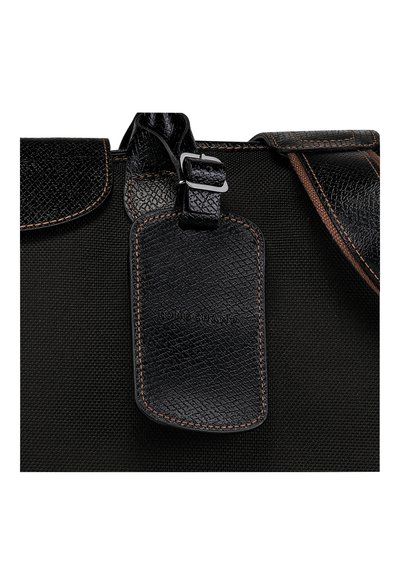 Schwarze Stofftasche mit einem strukturierten Lederanhänger für das Gepäck, auf dem "LONGCHAMP" geprägt ist, und kontrastierenden braunen Nähten an den Kanten.