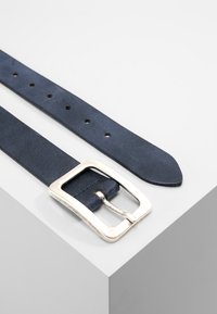 Navyblauwe leren riem met een zilveren rechthoekige gesp en meerdere verstelgaten; gladde textuur met een puntige uiteinde.