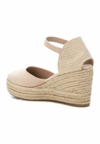 Sandalia de cuña en suave ante beige claro con suela de yute trenzada. Presenta una correa en el tobillo y un tacón con textura y patrón. Punta redondeada, superficie lisa.