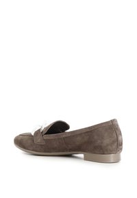 Scarpa slip-on in suede marrone con suola piatta, caratterizzata da un fiocco decorativo bianco sul vampo superiore e un design della punta semplice e arrotondato.