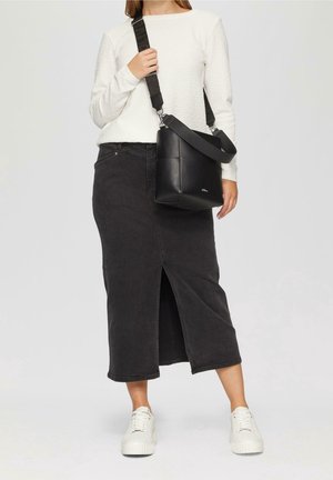 Jupe midi en denim noir avec fente à l'avant, associée à une chemise blanche à manches longues texturée. Accessoire : sac bandoulière noir avec sangle ajustable.