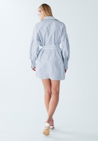 Triibuline särkkleit pikkade õhuliste varrukatega, piht lõigatud, valge ja mereväe sinise värvikombinatsiooniga. Valmistatud kergest kangast, pikkus kuni põlveni.