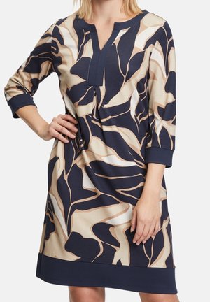 Laivastonsininen ja beige kuvioitu mekko, jossa V-pääntie ja kolme neljäsosaa hihat. Materiaalit ovat sileäpintaiset ja rento istuvuus.