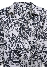 Chemise wrap florale noir et blanc avec col, taille cintrée et grands motifs de fleurs audacieux sur un tissu lisse.