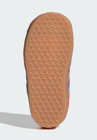 Sola de borracha com um padrão de colmeia, apresentando uma cor castanha clara. As bordas são texturizadas, fundindo-se com um cabedal têxtil multicolorido.