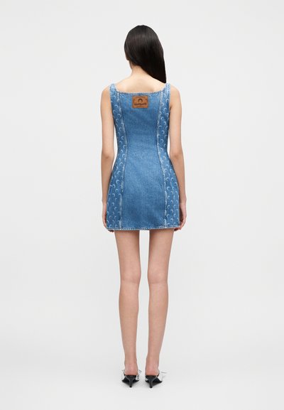 Μίνι φόρεμα από τζιν με εφαρμοστή γραμμή, σε μπλε χρώμα και διακοσμητικές ραφές. Διαθέτει ετικέτα με το λογότυπο στο πίσω μέρος και ελαφρώς φαρδύ τελείωμα.