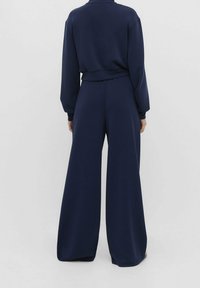 Marineblauwe jumpsuit met een aansluitend lijfje en wijde pijpen, met lange mouwen en een cropped taille voor een gestroomlijnde look.