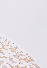 Witte kledingstuk van een gladde, zachte stof met ingewikkelde bloemenkantdetails aan één kant, wat een contrast in textuur en ontwerp creëert.