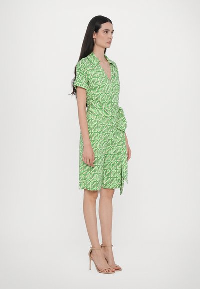 Robe verte à manches courtes avec un motif de feuilles, décolleté en V, ceinture à la taille et coupe décontractée, fabriquée en tissu léger.