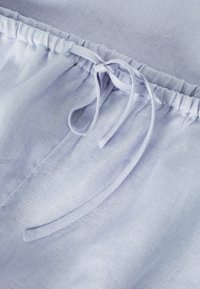 Světlomodrá lněná látka s nařaseným elastickým pasem. Obsahuje zavazovací šňůrku a hladkou strukturu. Jednoduchý, praktický design.