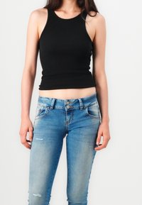 Black ribbed tank top paired with light blue skinny jeans featuring a faded finish and distressed detailing around the knees and pockets.