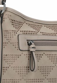 Beige Lederhandtasche mit perforiertem Muster, die über eine Reißverschlusstasche und einen Stoffgurt verfügt. Glatte Textur mit kontrastierenden schwarzen Akzenten.