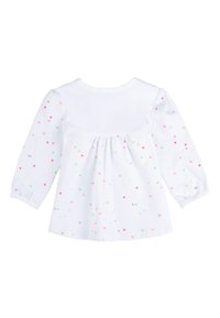 Top bianco a maniche lunghe con polka dot colorati in rosa, verde e giallo, con retro arricciato e tessuto morbido e leggero.