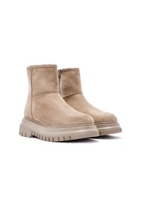 Botas de tobillo de ante beige con cremallera lateral, suela gruesa y estriada, y un detalle de costura mínimo. Textura suave con un diseño de punta redonda.