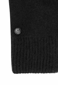 Schwarzer Strickpullover mit geripptem Muster am Saum. An der Seite ist ein Metall-Logoknopf als Detail angebracht.